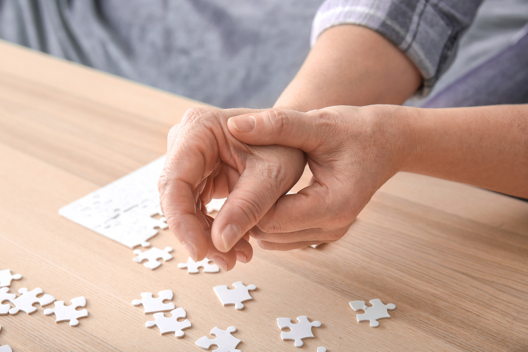 Senior Woman Suffering from Parkinson Syndrome Doing Puzzle at Home